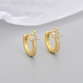 Close-up of gold flower hoop earrings with sparkling zircon stones on a soft fabric base - Gold White Zirconia