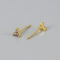 Detail van vergulde oorknopjes met een driehoekige tros paarse zirkonia steentjes - Paarse Steen Gouden Basis