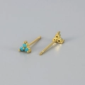 Macro-opname van minimalistische gouden klaver oorknopjes met blauwe edelstenen - Turquoise Steen Gouden Basis