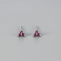Close-up of minimalist silver stud earrings with three-prong magenta zircon clover design - Rose Red Stone Silver Base