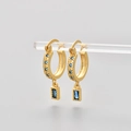 Detailed close-up of golden hoop earrings with blue zircon stones and engraved star patterns - Gold/Blue Zirconia