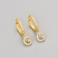 Detail view of gold earrings featuring a G letter pendant with micro-paved white zircons - Gold / G