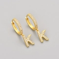 Macro shot of gold-plated hoop earrings with sparkling zircon-encrusted letter K pendant - Gold / K