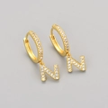 Macro shot of gold hoop earrings with pavé-set crystal letter N pendant for women - Gold / N