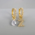Asymmetrische gouden oorbellen met letter Z en druppelzirkonia op grijze achtergrond - Koper / Goud-Letter Z