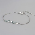 Macro view of S925 sterling silver stamp on wave bracelet with teal cubic zirconia - Platinum Color Blue Zirconia