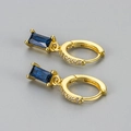 Detail van gouden oorringen met rechthoekige blauwe zirkoon en micro-pave kristallen - Goud Blauwe Steen