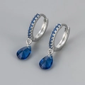 Macro shot of silver drop earrings featuring blue crystals and teardrop pendants - Platinum Blue Zirconia