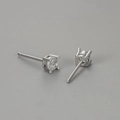 Macro close-up of classic four-prong round zircon stud earrings with silver metal finish - White Gold / 4mm