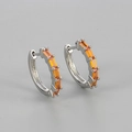 Close-up of silver huggie earrings featuring rectangular orange cubic zirconia stones - Silver / Orange