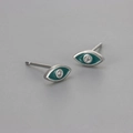 Macro shot of silver evil eye stud earrings with teal enamel and sparkling zircon - Copper / Silver Green