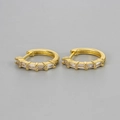 Detailed macro view of golden huggie earrings with five baguette-cut clear zircon stones - Gold/White Zirconia