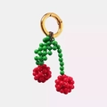 Handcrafted cherry charm with red and green beads featuring a gold spring clasp - Cherry