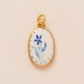 Detailaufnahme von ovalem Goldanhänger mit weißem Emaille und blauem Blumenmuster - Rund Blau Blume Stil