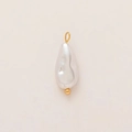 Detalle del colgante de perla barroca con aro chapado en oro de 18K en fondo crema - Perla de Agua Dolce