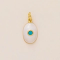 Detailed macro view of an oval gold pendant with white enamel and blue turquoise stone - December Pendant