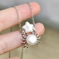 Silver crab pendant necklace featuring star-shaped and round white pearls in hand view - Silver Star Crab (Natural Pearl)