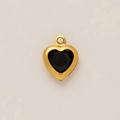 Detail view of heart-shaped gold pendant with central black gemstone inlay on light surface - Black Rhinestone Pendant