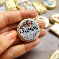 Detail view of a 18K gold plated ceramic flower pendant held to show handmade art - Sea Ceramic-Look Pendant