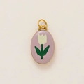 Gros plan d'un pendentif ovale doré avec paillettes violettes et motif floral de tulipe blanche - Breloque Fleur Rose