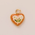 Close-up of heart-shaped pendant with orange enamel finish and delicate floral pattern - No.16 Red Heart Floral Style