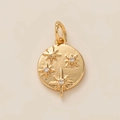 Dettaglio ravvicinato di un ciondolo tondo dorato con stelle e inserti in zircone - Pendente a Stelle Multiple / Oro