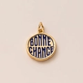Detailed macro view of gold round pendant with blue enamel and Bonne Chance engraving - Good Luck Text Style / Ticket Style Pendant