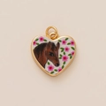 Gros plan d'un pendentif cœur doré orné d'un motif de cheval brun et de fleurs roses - Style Totem Cheval Coeur