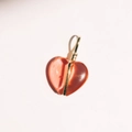 Detail van een rode doorschijnende hartvormige hanger met goudkleurige wikkeling - Dieprood Hart Edelsteen Hanger
