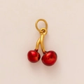 Detailed view of cherry pendant with dark red spheres and gold metal stem attachment - Cherry