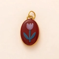 Close-up of a vintage red enamel oval pendant with a hand-painted tulip and gold metal edges - Red with Pink Flower Pendant