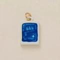 Detail eines rechteckigen weißen Keramikanhängers mit blauem Muster und Goldring - Gesalzener Fisch Anhänger