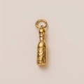 Macro shot of gold-plated bottle pendant featuring detailed floral relief carving - Chili Sauce Bottle
