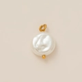 Detail van barokke parelhanger met 18K vergulde metalen ring op beige achtergrond - Platte Parelhanger