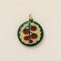 Detailed macro view of a round dark green enamel charm with a red cherry fruit pattern - Cherry Tomato