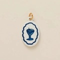 Detailed macro view of an oval ceramic pendant with blue cocktail pattern and gold ring - Wavy Wine Glass