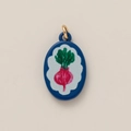 Detailed close-up of an oval enamel beet pendant with gold ring on beige background - Red Carrot