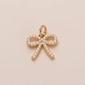 Détail d'un pendentif nœud en métal doré orné de micro-perles blanches sur fond chaud - Pendentif Nœud Papillon