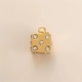 Macro detail of golden dice pendant with clear crystals on a minimalist background - Dice