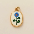 Detalle de colgante ovalado dorado con patrón floral azul sobre fondo beige minimalista - Óvalo (Marco Dorado Flor Azul) / Colgante Floral Azul Septiembre