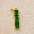 Close-up of three emerald green rectangular gems set in vertical gold-plated prongs - Bar Green Zirconia Pendant