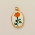 Détail du pendentif ovale en or avec broderie florale orange sur fond beige doux - Pendentif Fleur d'Octobre
