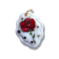 Vista macro del colgante de rosa de cerámica blanca con anillo de oro y dibujo floral - Rosa Roja