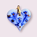 Detalle de un colgante de corazón cerámico con motivos florales azules y toques dorados - Flor de Corazón