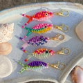 Close-up of five handmade colorful beaded fish keychains on white textured tray - Orange Pink Fish Charm