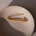 Elegante broche de imperdible chapado en oro con cuentas en una bandeja de cerámica - Cierre de broche