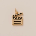 Detalle macro de un colgante de claqueta de cine bañado en oro 18K con esmalte negro - Colgante de Claqueta