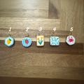 Detailed macro view of 5 assorted hand-painted 18K gold charms on a rustic wood background - No.1 Rhombus Lemon