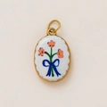 Detailed macro view of an oval 18K gold-plated pendant with pink flowers and a blue bow - White Base Pink Floral Bow Oval Style