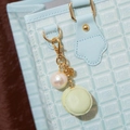 Eleganter Macaron-Taschenanhänger mit großer Perle und goldener Kette an blauer Tasche - Grüner Macaron-Anhänger